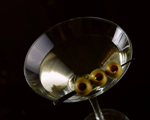 Martini cocktail met groene olijven op een zwarte achtergrond. — Stockfoto