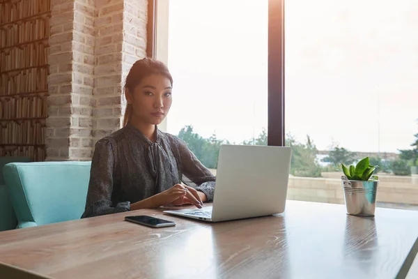 Attraktive Frau mit schönem Lächeln sitzt mit tragbarem Netzbuch im Café — Stockfoto