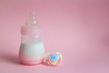 Süt şişesi bebek ve pembe arka plan üzerinde Emzik. metin için yer.