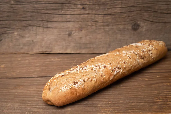 Baguete francês com sementes de gergelim no fundo de madeira velha — Fotografia de Stock