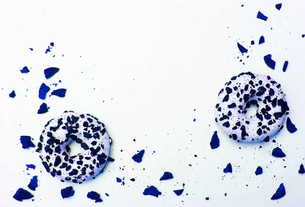 Dos donuts de color azul clásico con trozos de galletas en fondo blanco. —  Fotos de Stock