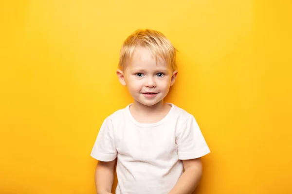노란 배경에 복제 공간 이 있는 흰색 티셔츠를 입고 있는 행복 한 푸른 눈동자의 2 년된 작은 금발 소년 — 스톡 사진