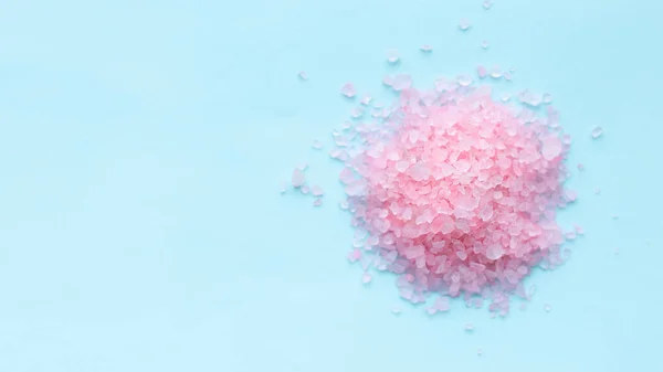 Heap of large sprinkled crystals of pink sea salt closeup on a blue background with place for text. body care concept. — Stock Image Heap Large Sprinkled Crystals Pink Sea Salt Closeup Blue Background Stock Photo