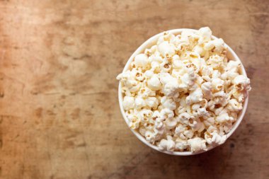 Tahta arka planda bir kasede patlamış mısır ve metin için yer var.