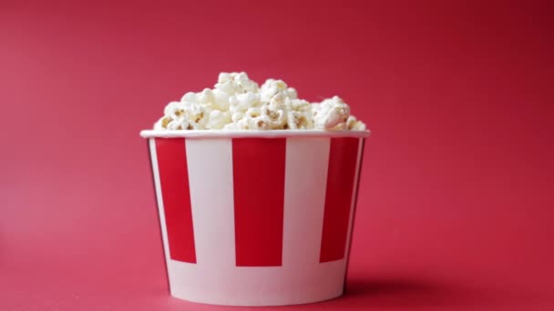 Niños caucásicos mano tomando palomitas de maíz de rayas caja de papel rojo y blanco — Vídeos de Stock