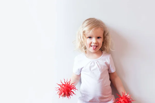 Little girl in white t-shirt playing with red virus model over white background..Virus, pandemic, quarantine and transmission concept . Concept of medicine and healthcare in the fight against viruses. — Stock Photo, Image