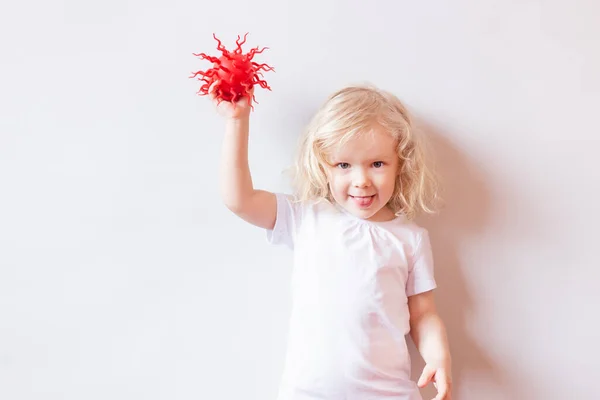 Menina em t-shirt branca brincando com o modelo de vírus vermelho sobre fundo branco.. Vírus, pandemia, quarentena e conceito de transmissão. Conceito de medicina e cuidados de saúde na luta contra os vírus . — Fotografia de Stock