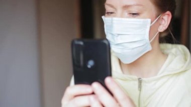Genç bayan blogcu Selfie çekiyor ya da koruyucu bir tıbbi maske takarak evde video görüşmesi yapıyor, covid 19 virüs salgını dünya karantinası, grip tehlikesi