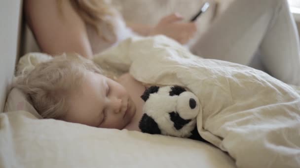 Girl use smartphone Near sleeping baby — Stock Video