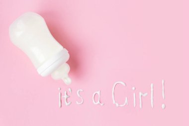 Pembe arka planda dökülen sütle birlikte plastik bebek şişesi. 