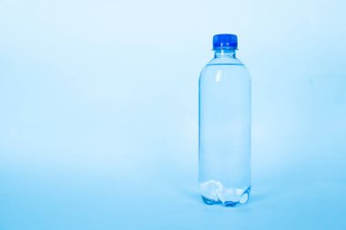 Temiz mavi arkaplanda plastik bir şişe maden suyu.