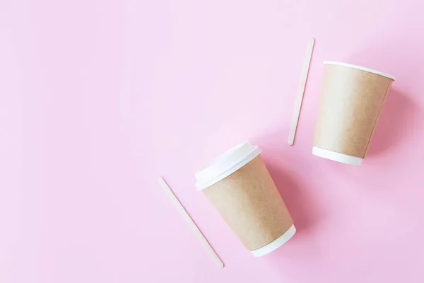 Eco due tazze di caffè di carta con bacchette di legno per mescolare su uno sfondo rosa . — Foto Stock