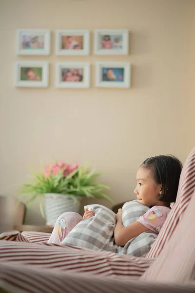 Asian child (girl) at home during Covid-19 RMO (restricted movement order) lockdown, watching TV