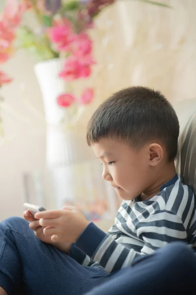 Asian child (boy) at home during Covid-19 RMO (restricted movement order) lockdown, playing with smartphone