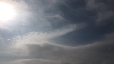 Beyaz bulutlar güneşin altında mavi gökyüzü üzerinde kaybolur. Hızlandırılmış hareket bulutlar mavi gökyüzü arka plan. 