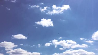 Beyaz bulutlar güneşin altında mavi gökyüzü üzerinde kaybolur. Hızlandırılmış hareket bulutlar mavi gökyüzü arka plan. 