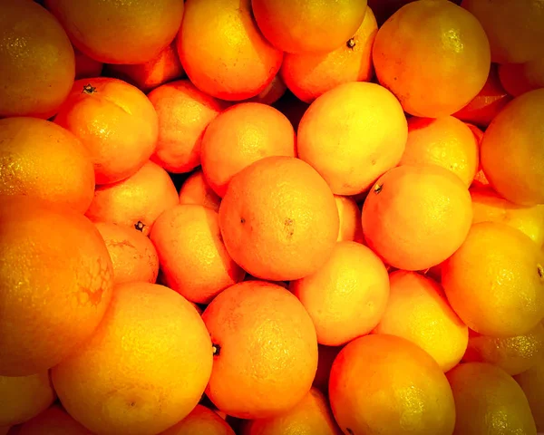 Fresh organic orange stand out among many large background orange in the market. Fruit of orange. Close-up orange texture.