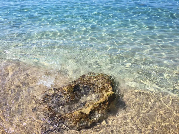 Νερό υφή στην Μεσόγειο θάλασσα ακτή. Πέτρα πάνω στην παραλία. Υφή του θαλασσινού νερού. Στην Αδριατική θάλασσα. Νερό φυσικό υπόβαθρο. — Φωτογραφία Αρχείου