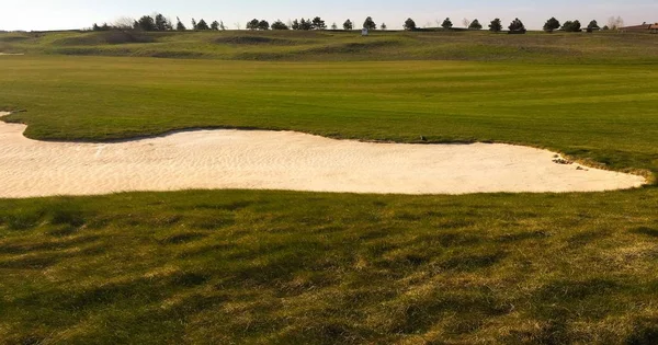 午後の日差しでバンカーとグリーンのゴルフ。ゴルフ白い砂トラップと緑のパノラマ風景。ゴルフ場高架道路. — ストック写真