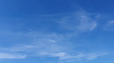 Mavi gökyüzündeki sıcak güneşte beyaz bulutlar kaybolur. Hızlandırılmış hareket bulutları, mavi gökyüzü arkaplanı ve güneş