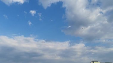 Mavi gökyüzündeki sıcak güneşte beyaz bulutlar kaybolur. Hızlandırılmış hareket bulutları, mavi gökyüzü arkaplanı ve güneş