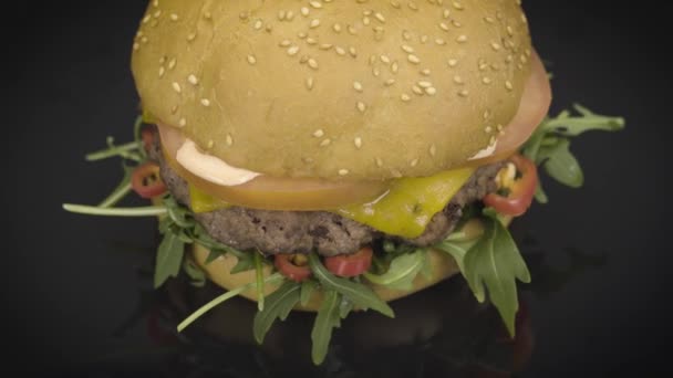 Смачний бургер, що обертається на чорному — стокове відео