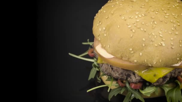 Smakelijke Hamburger draaien op zwart — Stockvideo