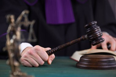 Erkek yargıç mahkeme salonunda tokmağa vuruyor.