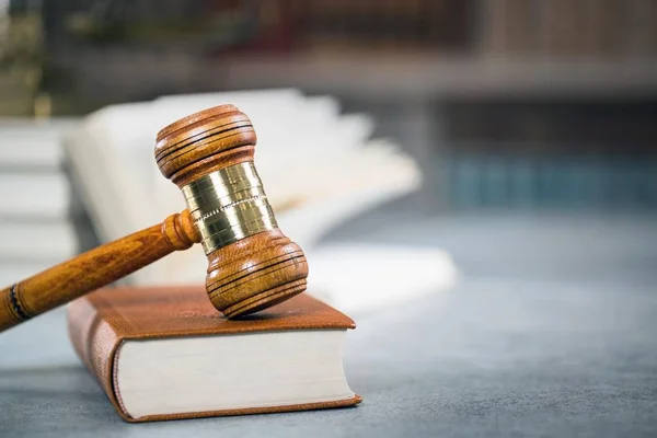 Gesetzeskonzept - offenes Gesetzbuch mit einem hölzernen Richtergabel auf dem Tisch in einem Gerichtssaal oder einer Strafverfolgungsbehörde auf blauem Hintergrund. Kopierraum für Text — Stockfoto