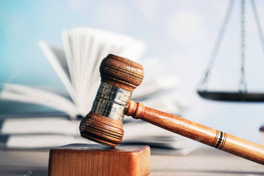 Law concept - Open law book with a wooden judges gavel on table in a courtroom or law enforcement office on blue background. Copy space for text