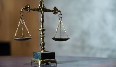 Hukuk ve Adalet 'in sembolü hâlâ hayattadır. Masa arkasındaki teraziler..