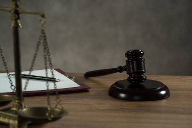 Ahşap masa arkasında hukuk ve adalet sembolleri - tokmak, terazi.
