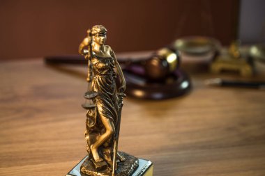 Ahşap masa arkasında hukuk ve adalet sembolleri..