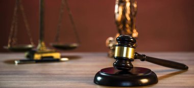 Ahşap masa arkasında hukuk ve adalet sembolleri..