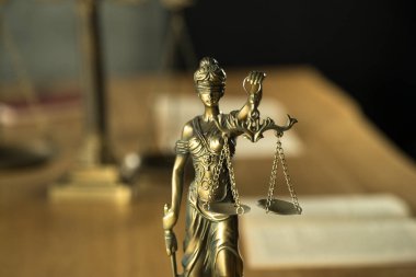 Kör Goddes Themis ahşap masa arkaplanında bulanık belgelerle terazi tutuyor.