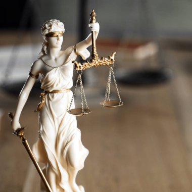 Kör Goddes Themis ahşap masa arkaplanında bulanık belgelerle terazi tutuyor.