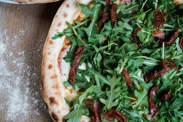 Italian pizza with arugula and cured sausage