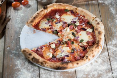 Tahta masada taze pişmiş pizza ve malzemeler.