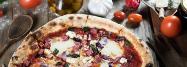 Tahta masada taze pişmiş pizza ve malzemeler.