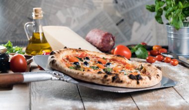 Kürek taze pişmiş pizzayı ahşap masaya koyar.