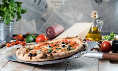 Kürek taze pişmiş pizzayı ahşap masaya koyar.