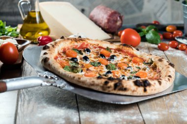 Kürek taze pişmiş pizzayı ahşap masaya koyar.