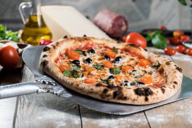 Kürek taze pişmiş pizzayı ahşap masaya koyar.