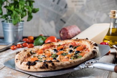 Kürek taze pişmiş pizzayı ahşap masaya koyar.