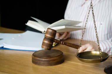 El ele tutuşmak ve kitap okumak, arka planda adalet terazisi. Hukuk hukuku ve adalet kavramı.