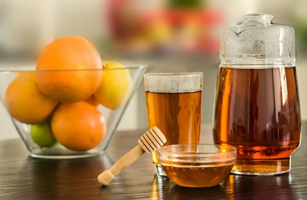 Krug und Glas mit heißem schwarzen Tee mit Schalen mit Honig und Früchten — Stockfoto