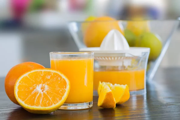 Glas und Saftpresse mit frisch gepresstem Orangensaft. — Stockfoto