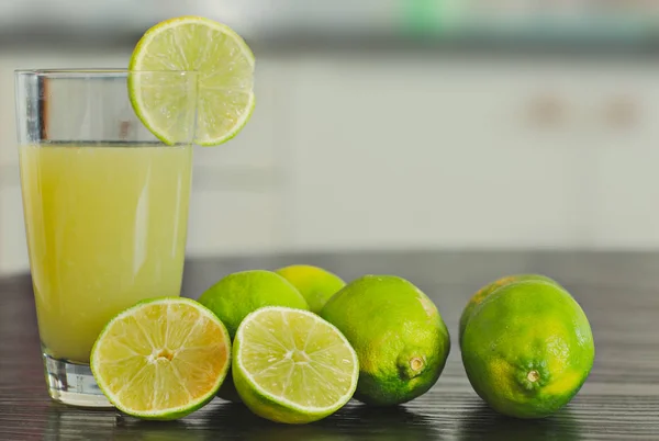 Ποτήρι φρεσκοστυμμένο χυμό λεμονιού με φέτες και ολόκληρα λεμόνια — Φωτογραφία Αρχείου