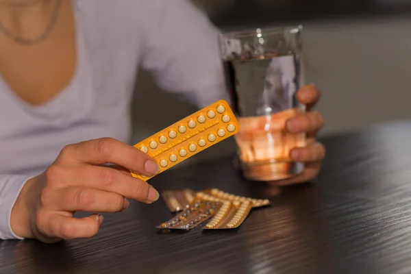 Женщина с упаковкой противозачаточных таблеток и стаканом воды . — стоковое фото