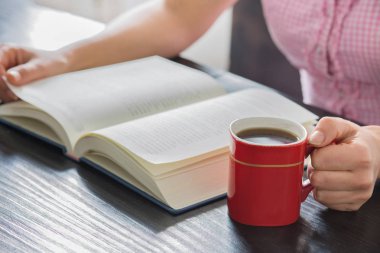 Yığın kapalı kitap ve kahve ev ile açık kitap tutan eller kadın..
